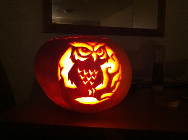 Glowing pumpkin with owl carved into the front